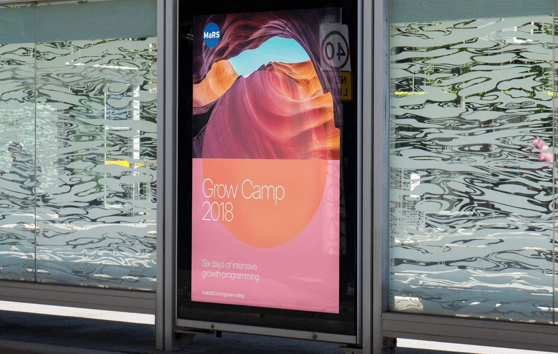 MaRS Grow Camp 2018 poster displayed in a transit shelter, featuring abstract canyon imagery, pink and orange gradient design, and event details