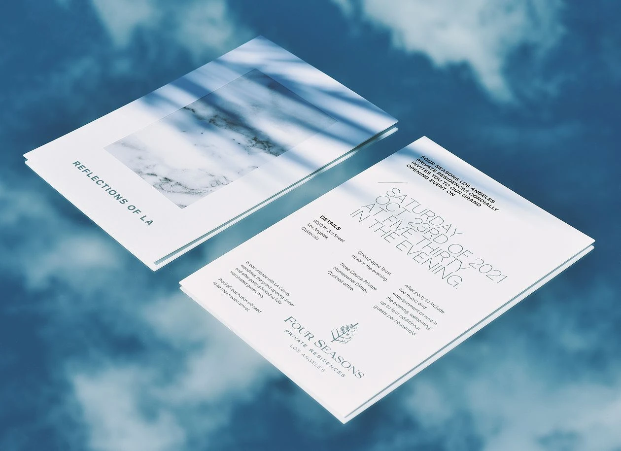Two printed cards for Four Seasons ‘Reflections of LA’ shown on a blue background, featuring event details and minimalist typography