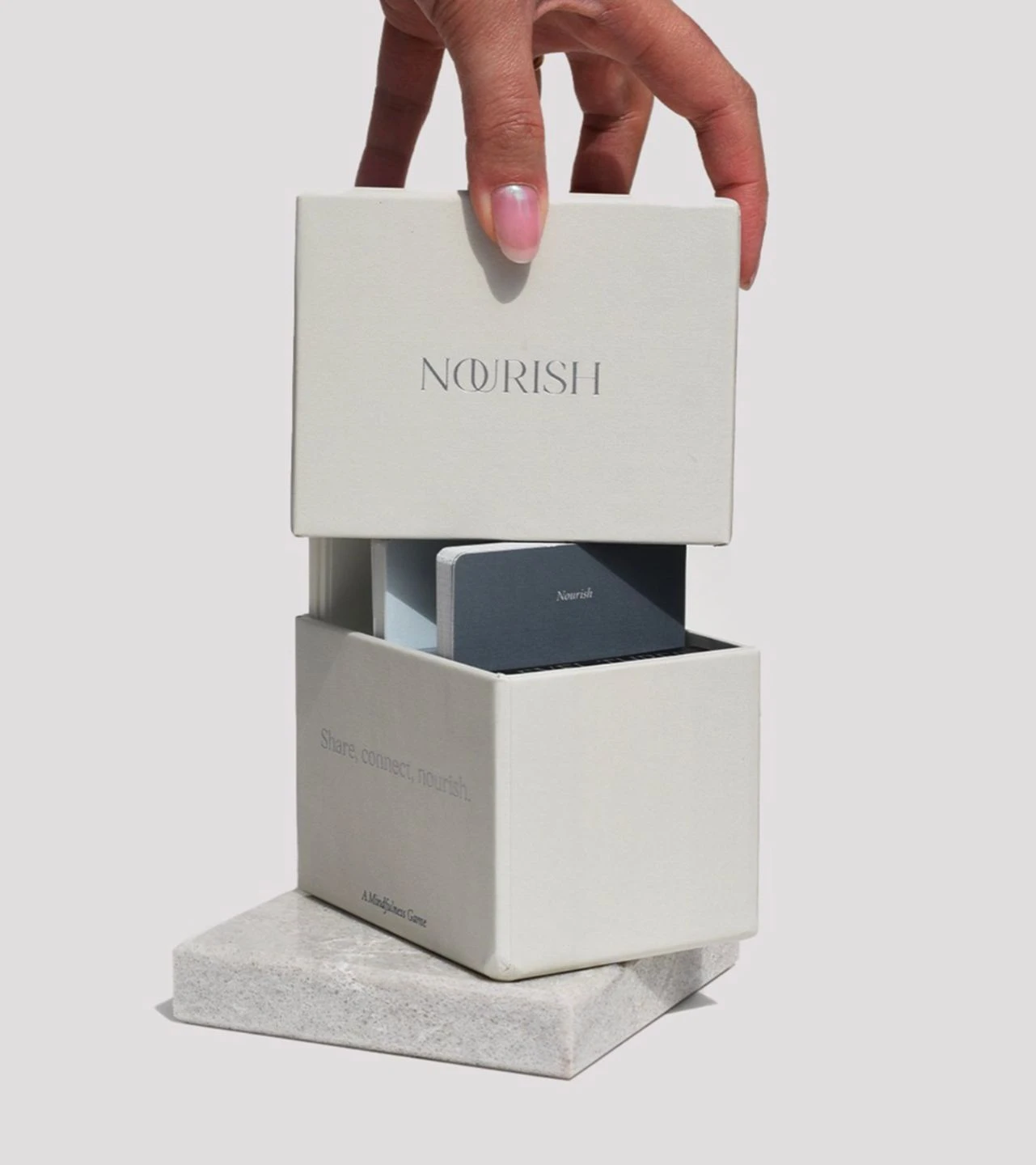 Sensei Nourish card game gifting packaging with a hand opening the box to reveal the card decks inside
