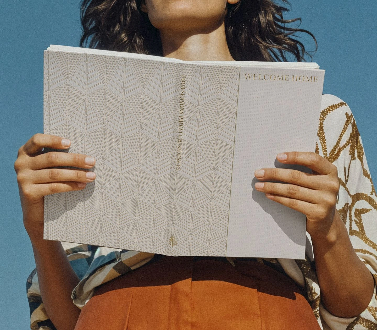 Four Seasons Residential welcome booklet design shown being held, featuring textured paper and geometric pattern.